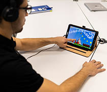 Ein Proband führt Testübungen auf einem Tablet, welches mit einer sensorgestützten Einlegesohle verbunden ist, durch. 