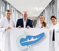 Prof. Dr. med. Roland S. Croner, Direktor der Universitätsklinik für Allgemein-, Viszeral-, Gefäß- und Transplantationschirurgie, Lutz Otto, Vorsitzender des Arbeitskreises der Pankreatektomierten AdP e.V., Fachärztin Dr. Sara. Acciuffi und Fachärztin Sara Al-Madhi stellen gemeinsam das neue Logo des Pankreaszystenpasses vor.